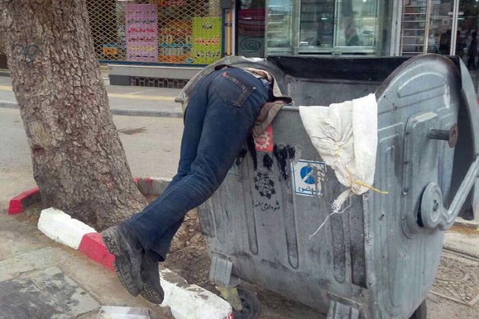 A man searching the garbage can for food due to widespread poverty